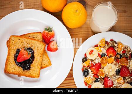 Table top image de pain grillé avec la confiture de canneberges de garnitures, fraise et mélange sain d'avoine fruits en plaque blanche sur table à manger en bois. Banque D'Images