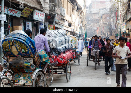 Homme transportant des vêtements et tissus sur un cycle rickshaw par ville de Dhaka, Bangladesh. Banque D'Images