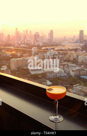 Verre de cocktail sur la table du bar sur le toit avec vue sur la ville d'antenne en arrière-plan Banque D'Images