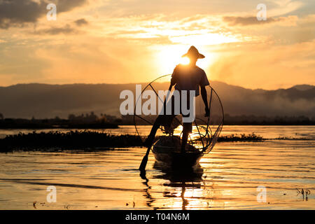 La pêche avec les pêcheurs traditionnels et en grosses mailles un-jambe unique style aviron pendant le coucher du soleil sur le lac Inle dans l'Etat Shan, Myanmar, Birmanie Banque D'Images