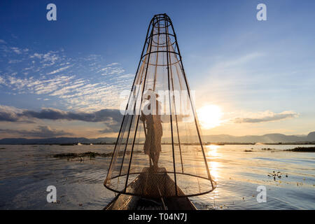La pêche avec les pêcheurs traditionnels et en grosses mailles un-jambe unique style aviron pendant le coucher du soleil sur le lac Inle dans l'Etat Shan, Myanmar, Birmanie Banque D'Images