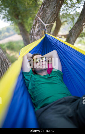 Photo de l'Homme à lunettes couché dans un hamac en forêt Banque D'Images