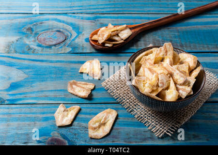 Chips de banane à l'intérieur pot en céramique bleu sur bois de pin. Banque D'Images