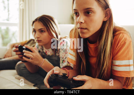 Close up of two teenage girls playing video game holding joysticks. De filles à la maison et jouer jeu vidéo avec beaucoup d'intérêt. Banque D'Images