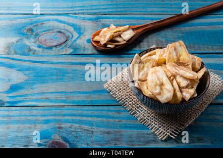 Chips de banane à l'intérieur pot en céramique bleu sur bois de pin. Banque D'Images