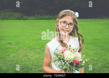 Sweet Girl de demoiselle d'enfant en robe blanche et verres avec wildflower et verdure posy - natural shot Banque D'Images