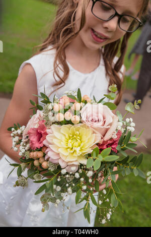 Girl holding de demoiselle petit Septembre saison rustique la main mariage bouquet : roses rose pastel, dahlia, gypsophile, astrantia, baies, feuillage Banque D'Images