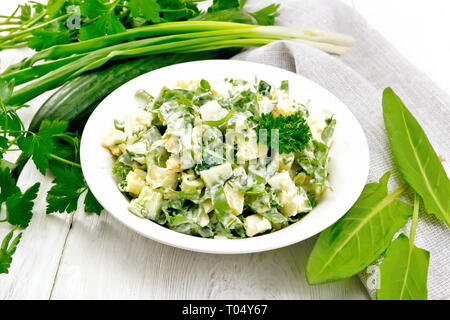 Salade de concombre, oseille, pommes de terre bouillies, les oeufs et les herbes, habillé avec de la mayonnaise dans une assiette blanche, le persil, les oignons verts et la serviette contre l'arrière Banque D'Images