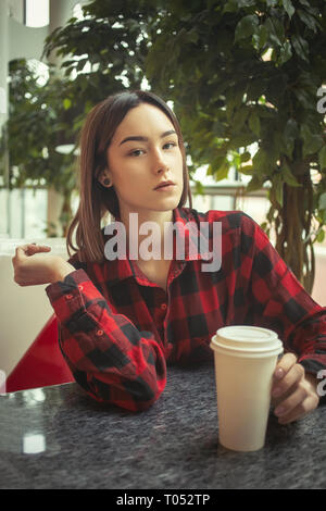 Sad young woman sitting in cafe, looking at camera Banque D'Images