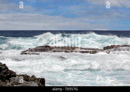 Les vagues en colère et le matériel roulant se briser contre les plates-formes de pierre de corail et de la mise à niveau de l'orifice de baignade naturel pendant la marée haute à une île tropicale Banque D'Images