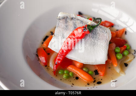 Filet de sandre à l'étuvée gros plan avec des légumes, piment, tomate, oignon, carotte mini avec la sauce servi sur table dans un restaurant. Concept professi Banque D'Images