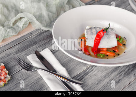 Filet de sandre à l'étuvée gros plan avec des légumes, piment, tomate, oignon, carotte mini avec la sauce servi sur table dans un restaurant. Concept professi Banque D'Images