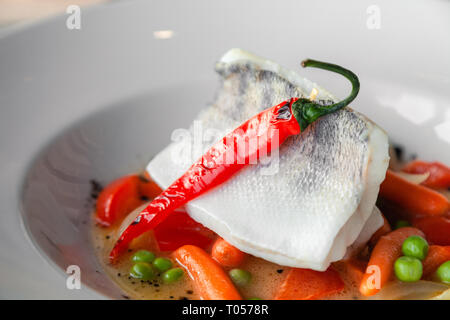 Filet de sandre à l'étuvée gros plan avec des légumes, piment, tomate, oignon, carotte mini avec la sauce servi sur table dans un restaurant. Concept professi Banque D'Images