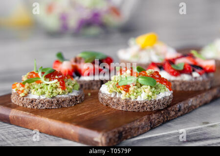 Сloseup ensemble macro de différentes bouchées sur la mode du nord smorrebrod le pain de seigle avec du caviar rouge et d'avocat, de fraises et de vinaigrette balsamique. Con Banque D'Images