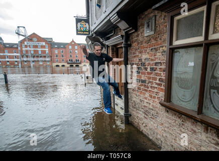 Un membre du personnel de la Kings Arms à York sautille à travers l'eau d'inondation après la rivière Ouse éclate ses banques, comme des avertissements d'inondation restent en place à travers le Royaume-Uni. Banque D'Images