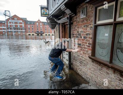 Un membre du personnel de la Kings Arms à York sautille à travers l'eau d'inondation après la rivière Ouse éclate ses banques, comme des avertissements d'inondation restent en place à travers le Royaume-Uni. Banque D'Images