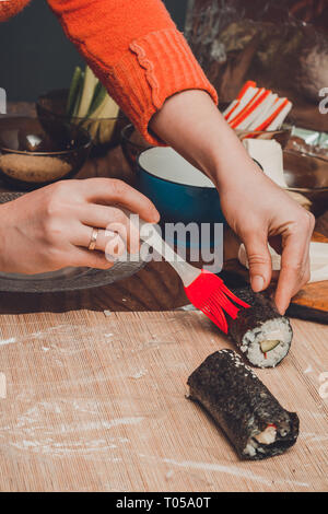 Le chef du restaurant est le pinceau de l'onction de la sauce sur le rôle de sushi 2019 Banque D'Images