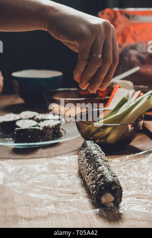 Women's Hands close-up dans un restaurant saupoudrer l'huile de sésame pendant la préparation de sushi 2019 Banque D'Images