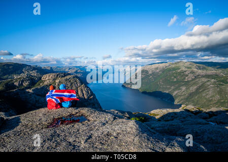 Vue sur le fjord Lysefjord du Preikestolen. Couple de touristes avec le pavillon de la Norvège visiter les attractions naturelles. Banque D'Images