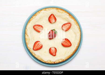 Tout un gâteau au fromage classique avec des fraises sur un fond blanc. Vue d'en haut. Banque D'Images