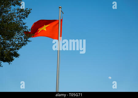 Comme la lune se lève à l'arrière-plan, un drapeau vietnamien est forme sur le jardin du port de Bach Dang bankside de l'Rạp Soài River. Banque D'Images