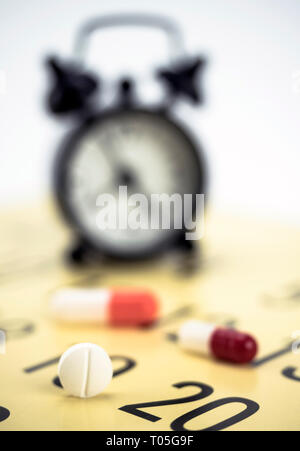 Pilules sur un calendrier à côté d'une horloge, conceptual image Banque D'Images