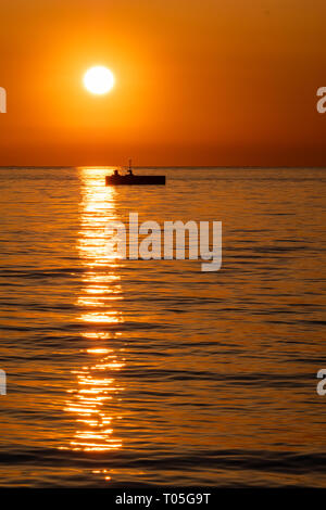 Silhouette de grand soleil coucher de soleil à partir de la bouée sur un quai Molo Audace à Trieste, Italie Banque D'Images