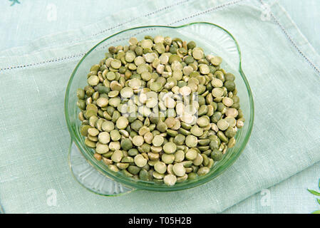 Diviser les pois verts dans un plat en verre vintage sur de vieilles serviettes en lin Banque D'Images