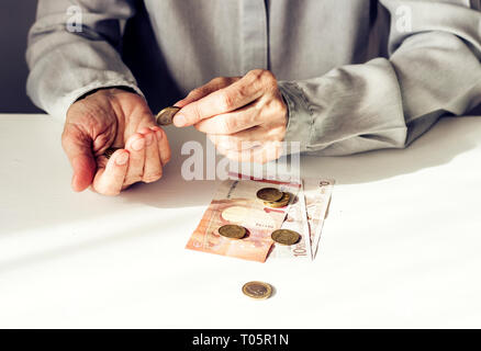 Pièces en euro et old woman's hands on white background with copy space Banque D'Images