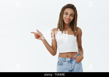 Laissez-nous aller ensemble explorer endroit fantastique pour copier l'espace. Charmante fille hipster à peau sombre avec des dreads jaune pointant vers la gauche charmante posing Banque D'Images