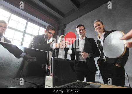 Les gens jouent au ping-pong sur la table de bureau avec des ordinateurs portables Banque D'Images