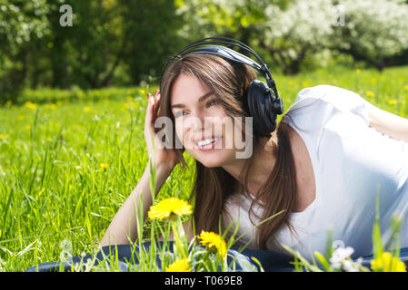 Jeune femme brune avec des écouteurs à écouter la musique en plein air aux beaux jours d'été Banque D'Images