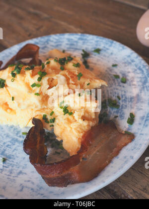 De délicieux œufs brouillés avec du bacon et la ciboulette sur une table en bois rustique, tsty concept petit-déjeuner Banque D'Images
