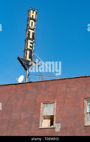 Signe en forme de flèche sur le toit d'un hôtel de couleur bourgogne abandonné contre le ciel bleu, orientation verticale Banque D'Images