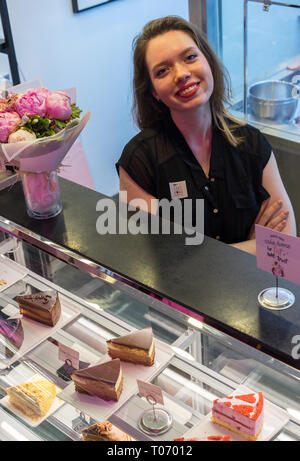 Une belle femme caucasienne heureuse vend des gâteaux dans une boulangerie Banque D'Images