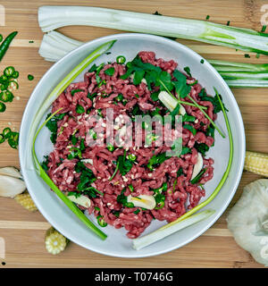 Boeuf haché cru et légumes piments et l'ail réfrigéré avec planche à découper en bois Banque D'Images