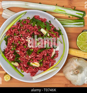 Boeuf haché cru et légumes piments et l'ail réfrigéré avec planche à découper en bois Banque D'Images