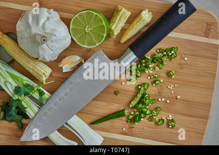 Piments Thaï asiatique et les légumes les ingrédients sur planche à découper avec Couteau Santoku Banque D'Images