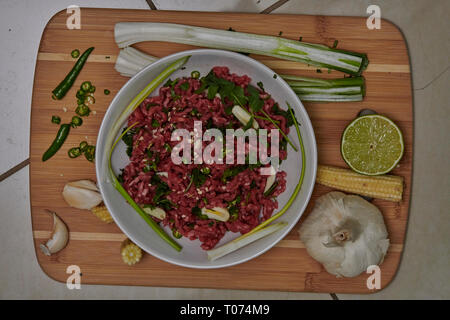 Boeuf haché cru et légumes piments et l'ail réfrigéré avec planche à découper en bois Banque D'Images