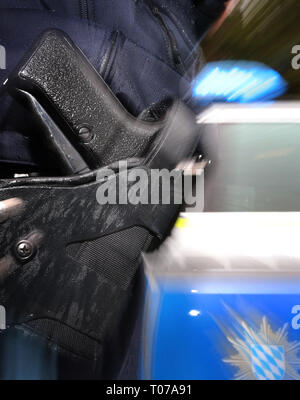 Kempten, Allemagne. Mar 15, 2019. ILLUSTRATION - un agent de police avec un pistolet à sa ceinture est debout devant une voiture de patrouille (brouillé par effet de zoom). Sur les statistiques criminelles 18.03.2019 bavarois 2018 sera annoncé. Credit : Karl-Josef Opim/dpa/Alamy Live News Banque D'Images