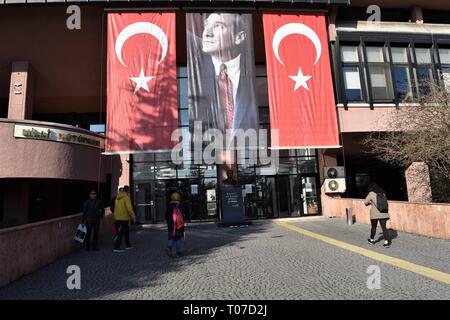 18 mars 2019, la Turquie, Ankara : les gens marcher vers l'édifice de la Bibliothèque nationale comme un portrait de Mustafa Kemal Atatürk, fondateur de la Turquie moderne, le président turc et drapeaux nationaux sont pendus à l'occasion du 104e anniversaire de la victoire de Canakkale. Photo : Altan Gochre dans le monde d'utilisation | Banque D'Images