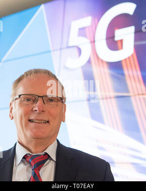 Mainz, Allemagne. 18 Mar, 2019. Jochen Homann, Président de l'Agence fédérale des réseaux, s'élève face à un écran avec l'inscription '5G'. Du mardi (19.3.), l'Agence fédérale des réseaux mettra aux enchères 41 blocs de fréquences à divers fournisseurs. La vente aux enchères doit durer plusieurs semaines. Credit : Boris Roessler/dpa/Alamy Live News Banque D'Images