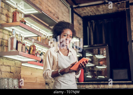 Charmant bar Afro employé remplissant Formulaire de commande avec tablet Banque D'Images