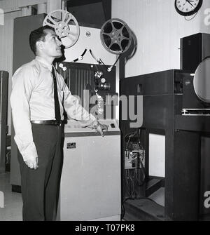 60 ans, technicien du film debout à côté d'un rouleau à rouleau film machine et autres équipements de radiodiffusion, l'Arabie Saoudite. Banque D'Images