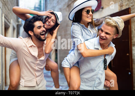 Happy friends enjoying piggyback tandis que les sites touristiques de la ville. Banque D'Images