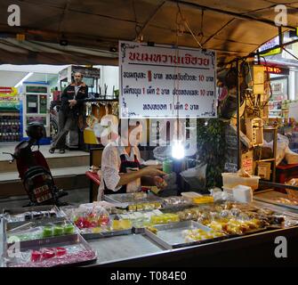 CHIANG MAI, THAÏLANDE—MARS 2018: Une femme se tient derrière ses expositions de spécialités thaïlandaises pour la vente au marché de nuit à Chiang Mai. Banque D'Images