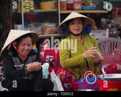 CAN THO, VIETNAM--MARS 2018: Deux vendeurs de rue féminins sourire aux clients au marché Cho an Binh. Banque D'Images