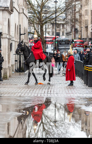 Relève de la Garde cérémonie montés après de fortes pluies. Traduit par flaque. Les gardiens de la vie de la Household Cavalry en hiver manteaux uniforme Banque D'Images