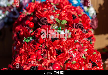 Composition de petites fleurs faites à la main, rouge et bordeaux roses, perles, feuilles vertes closeup Banque D'Images