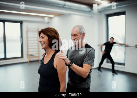 A senior woman in gym faire de l'exercice avec un entraîneur personnel. Banque D'Images